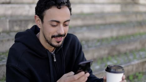 Zufriedener-Mann-Mit-Smartphone-Und-Kaffee-Zum-Mitnehmen